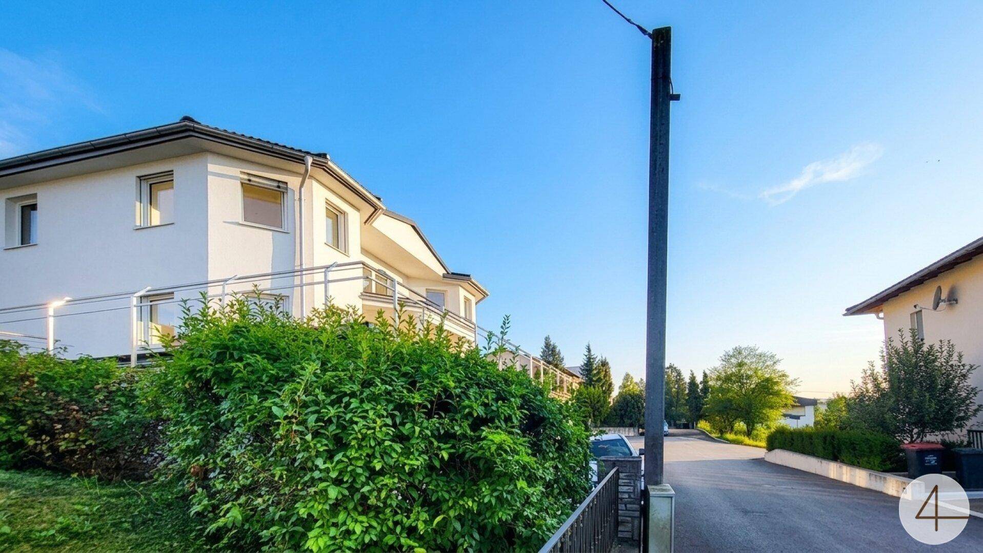 Seitenansicht des Hauses mit gepflegter Hecke und Blick auf die ruhige Wohnstraße.