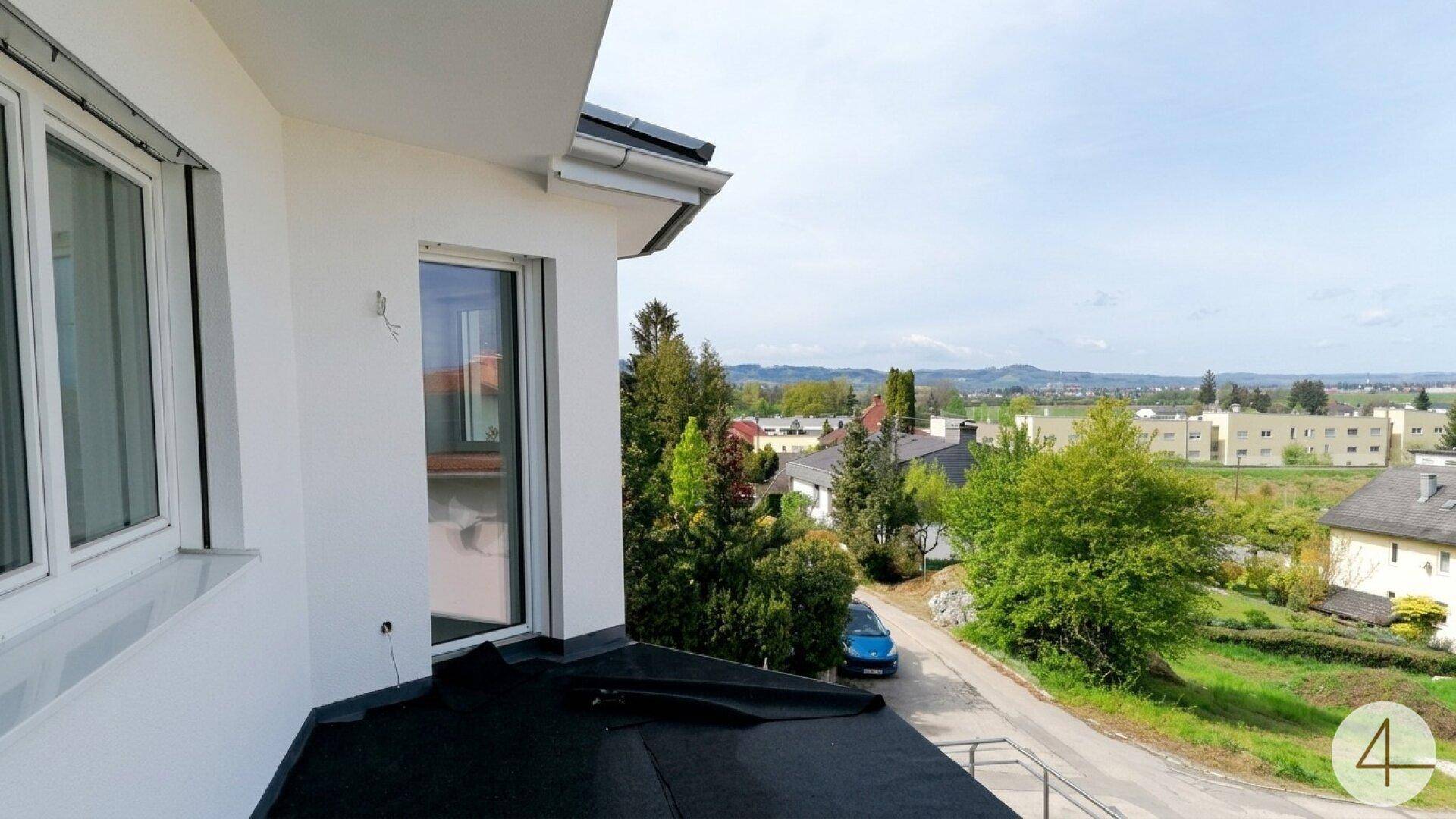 Ausblick von einem oberen Stockwerk über die umliegende Wohngegend und weite Landschaft.