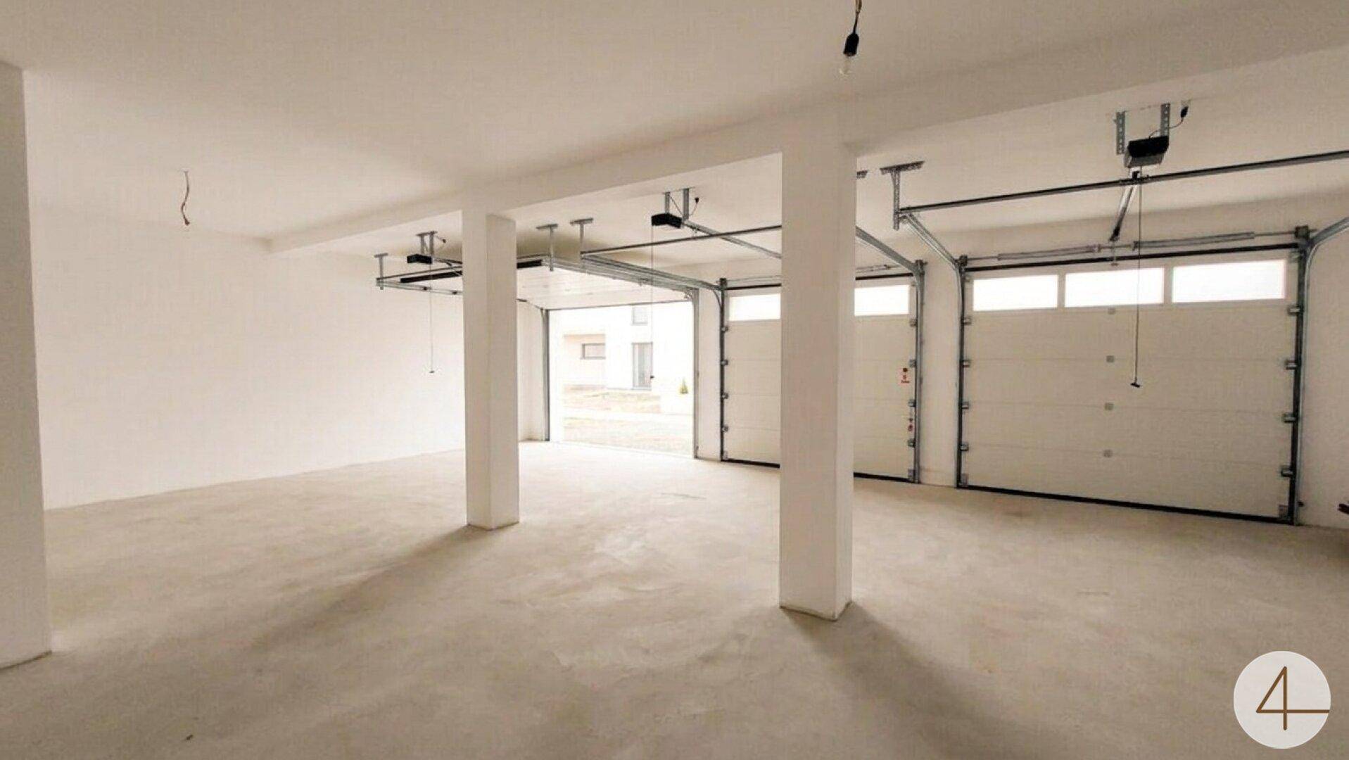 Geräumige Garage mit mehreren Toren und viel Platz für Fahrzeuge und Lagerung.