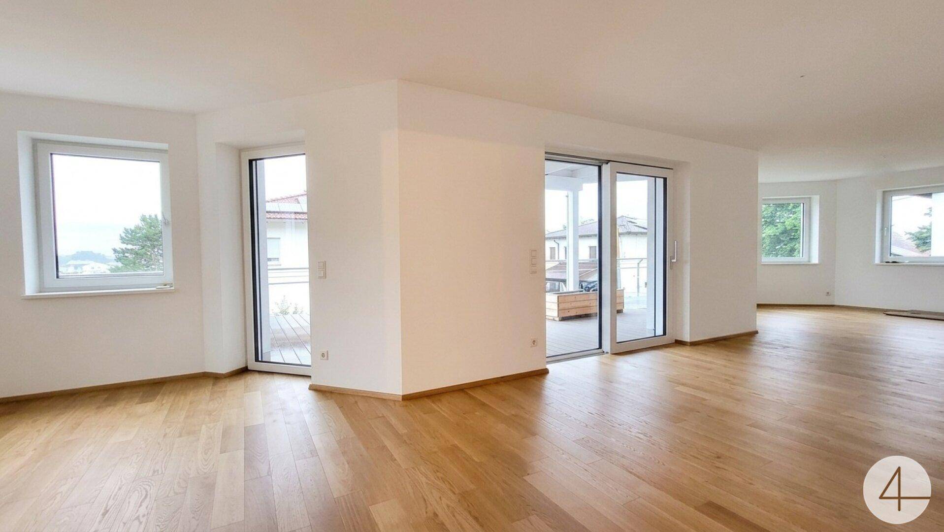 Geräumiger Wohnbereich mit Holzboden und großen Schiebetüren zur sonnigen Terrasse.