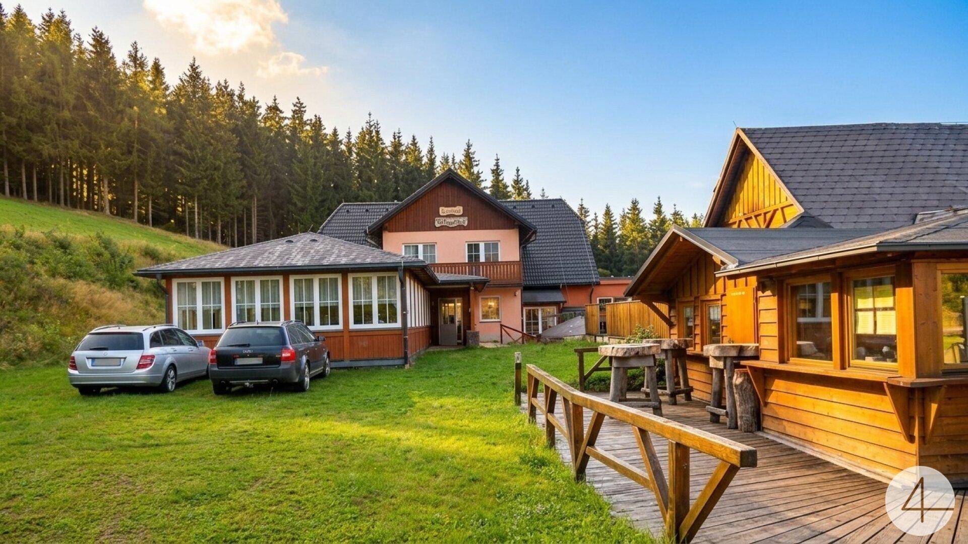 Mehrere Gebäude im alpinen Stil mit Holzverkleidung und großem Rasenbereich, umgeben von Wald und Bergen.