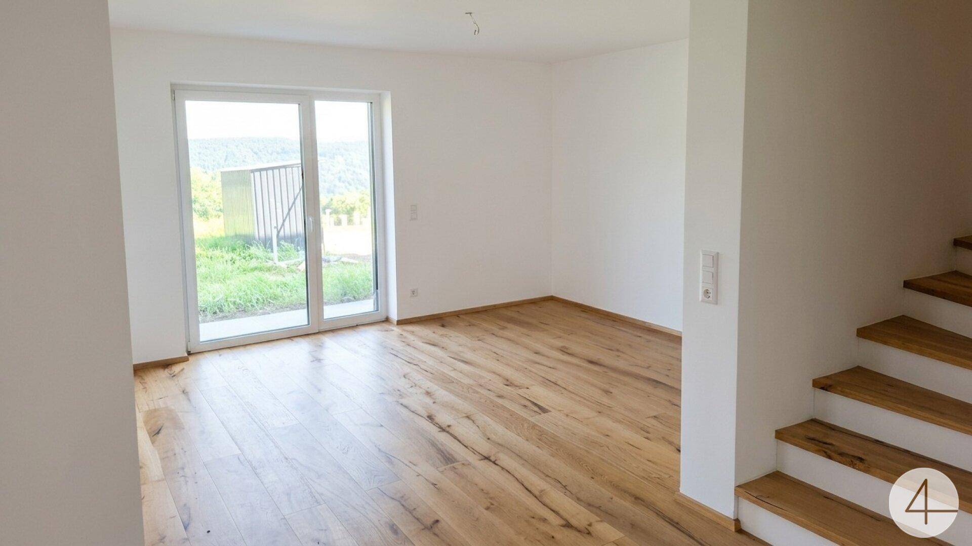 Lichtdurchfluteter Wohnbereich mit Holzboden und großer Schiebetür, die direkten Zugang zur Terrasse bietet.