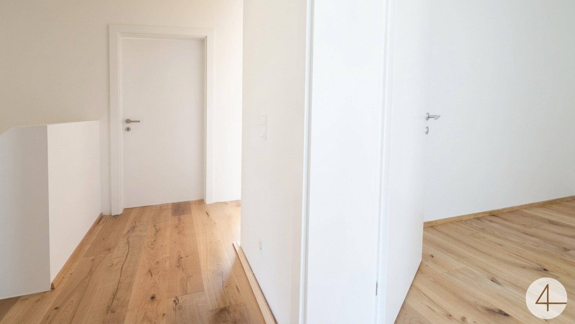 Heller Flur mit Holzboden und weißen Türen, der die verschiedenen Räume des Hauses miteinander verbindet.