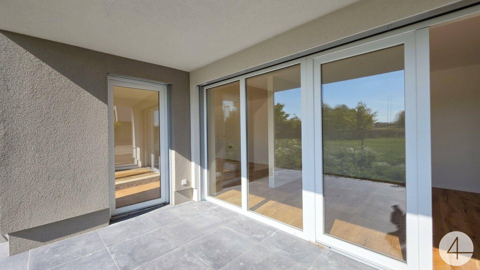 Moderne Terrasse mit grauen Fliesen und großen Schiebetüren, die den Übergang zum Innenbereich ermöglichen.