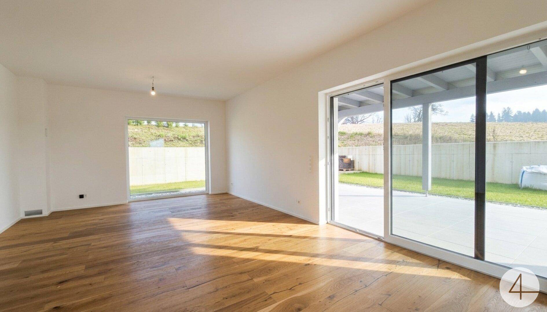 Helles Wohnzimmer mit Holzboden, großen Fenstern und direktem Zugang zur Terrasse.