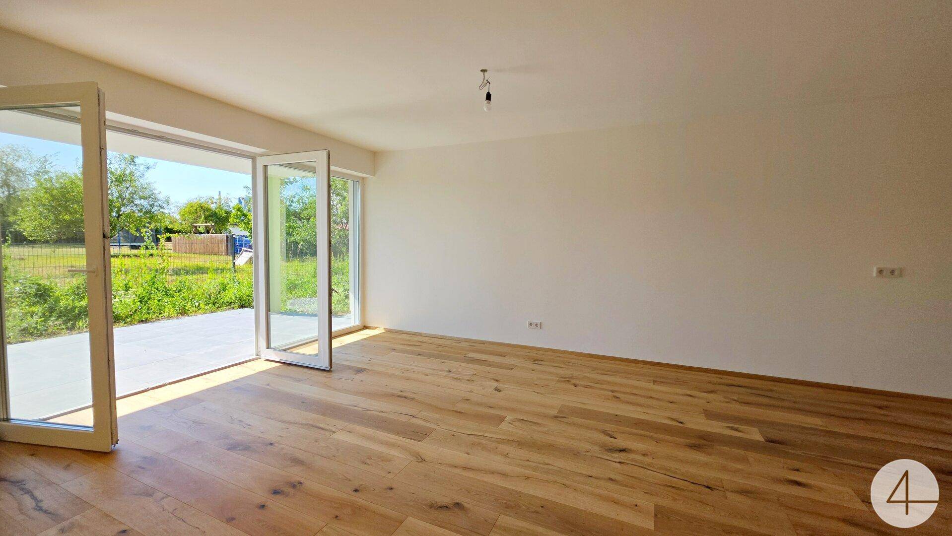 Heller Wohnraum mit Eichenparkett und großen Glastüren zum Terrassenbereich.
