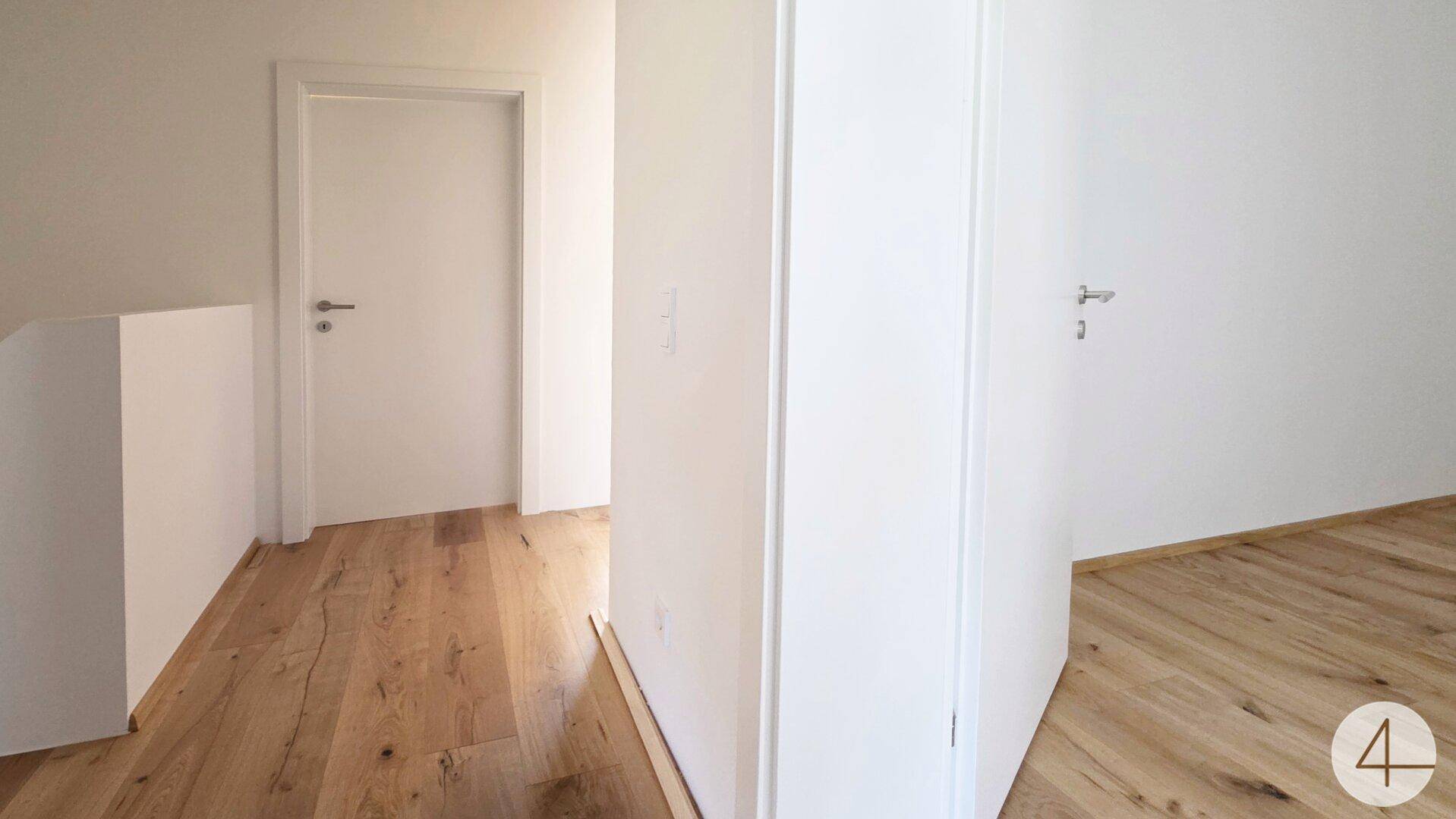 Heller Flur mit Holzboden und weißen Türen in einem neuwertigen Zustand.