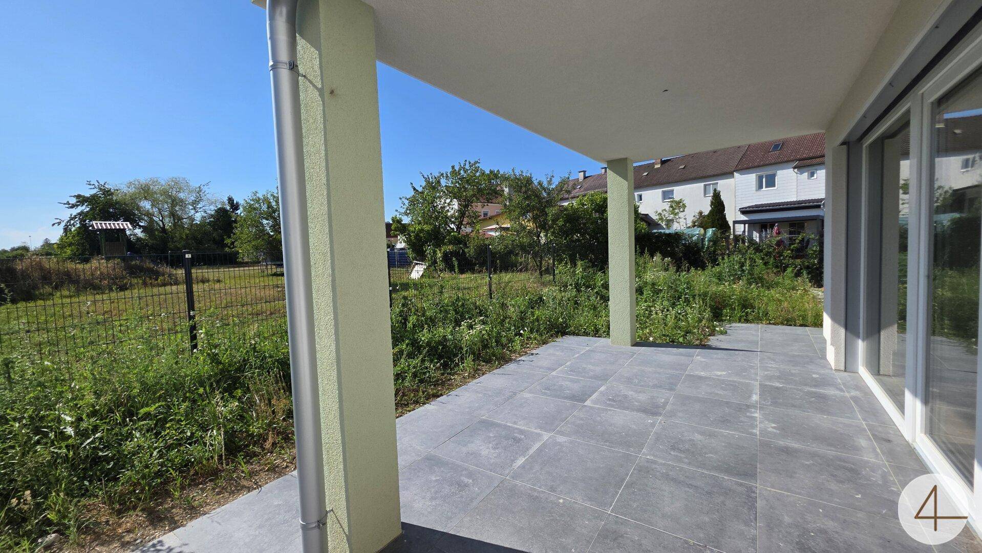 Überdachte Terrasse mit grauen Fliesen und weitem Blick auf die umliegende Natur.