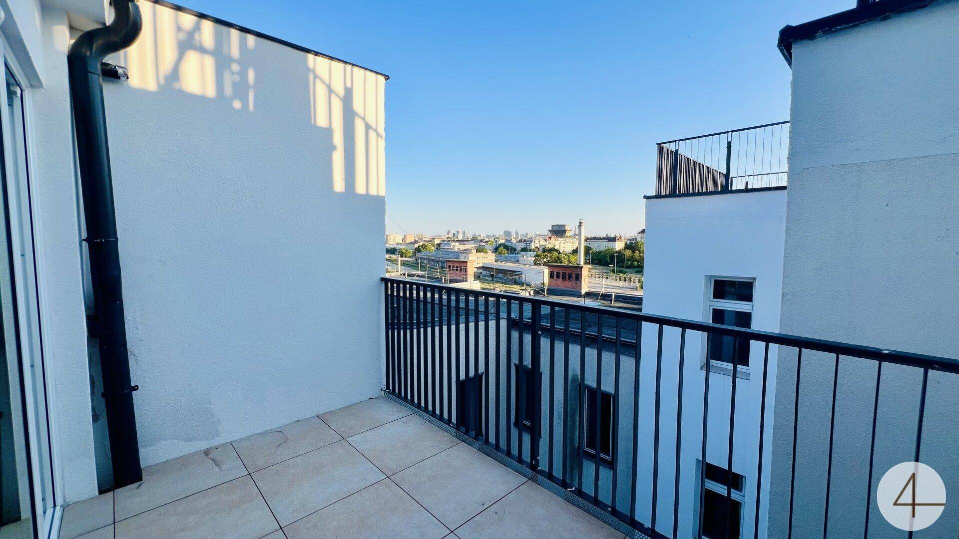 Gefliester Balkon mit schwarzem Geländer bietet einen weiten Blick über die Stadtlandschaft.