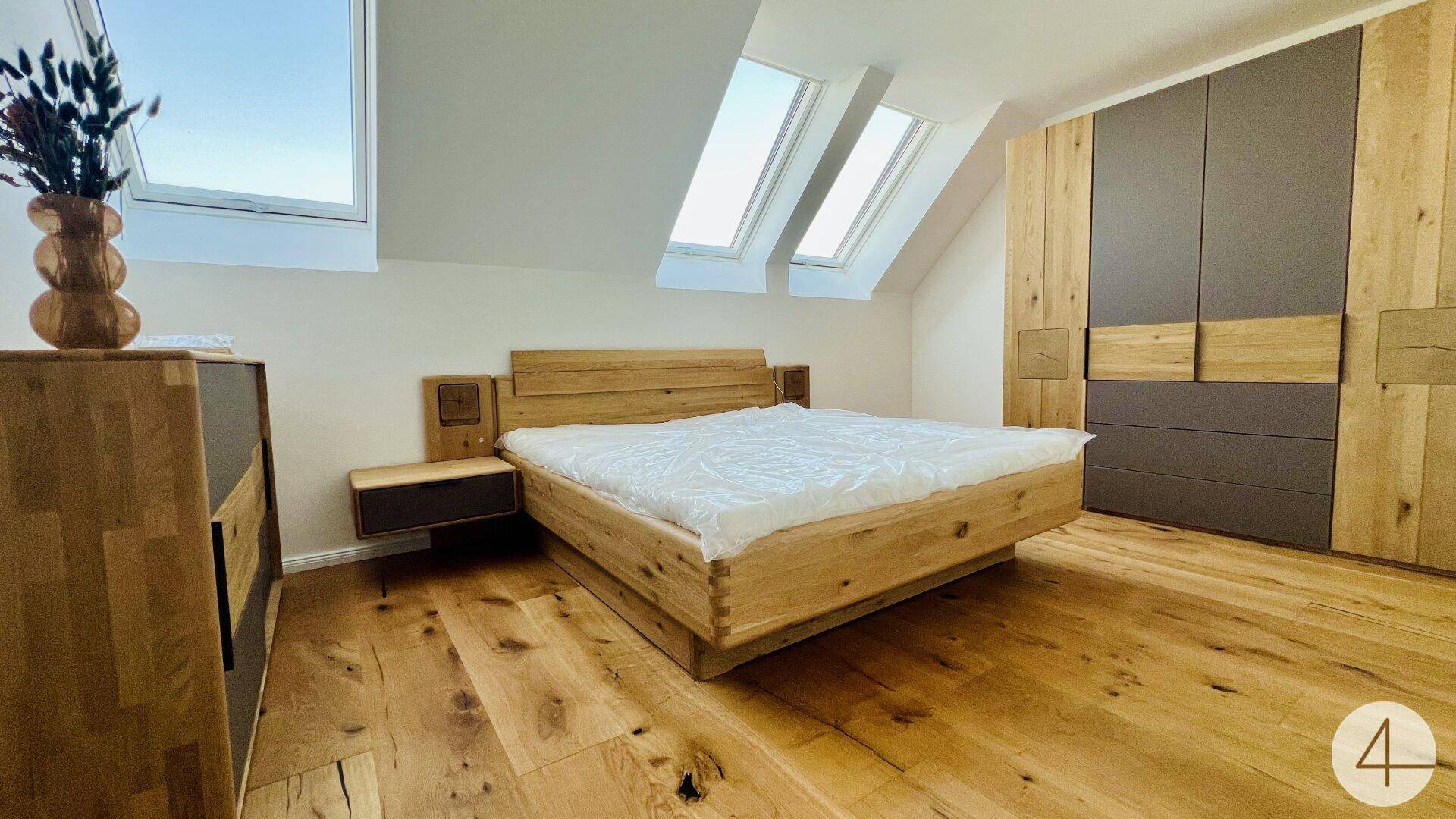 Gemütliches Schlafzimmer mit Holzbett, Einbauschrank und Dachfenstern unter der Dachschräge.