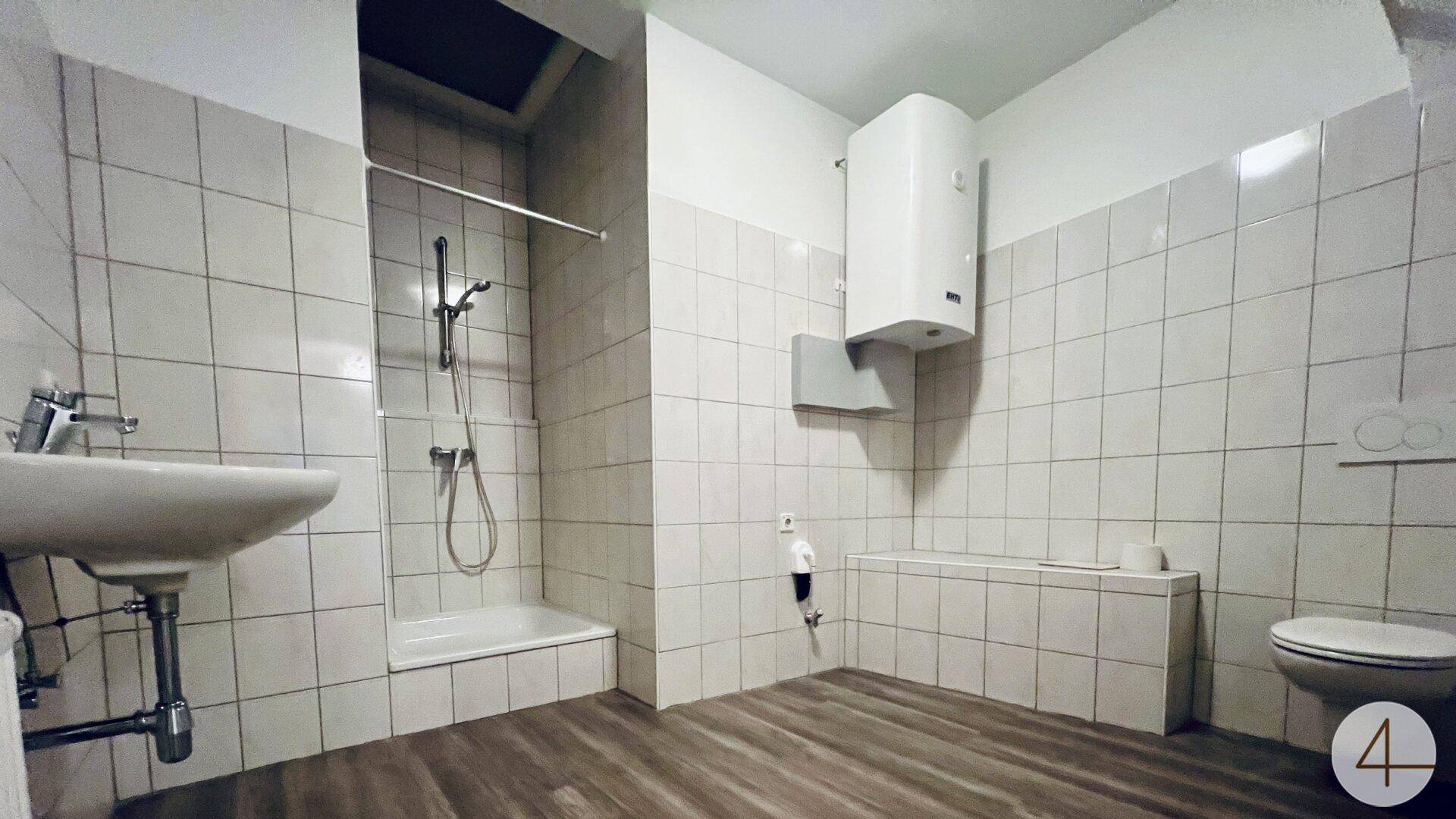 Funktionales Badezimmer mit Dusche, WC, Waschbecken und weißen Fliesen an den Wänden.