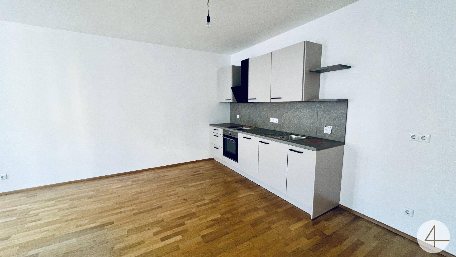 Moderne Einbauküche mit hellgrauen Schränken, integrierten Geräten und Holzboden.