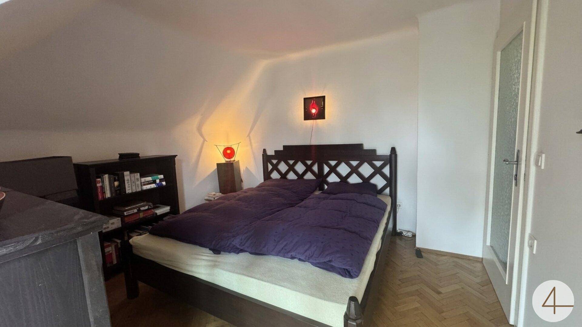 Schlafzimmer im Dachgeschoss mit Holzbett und schrägen Wänden.