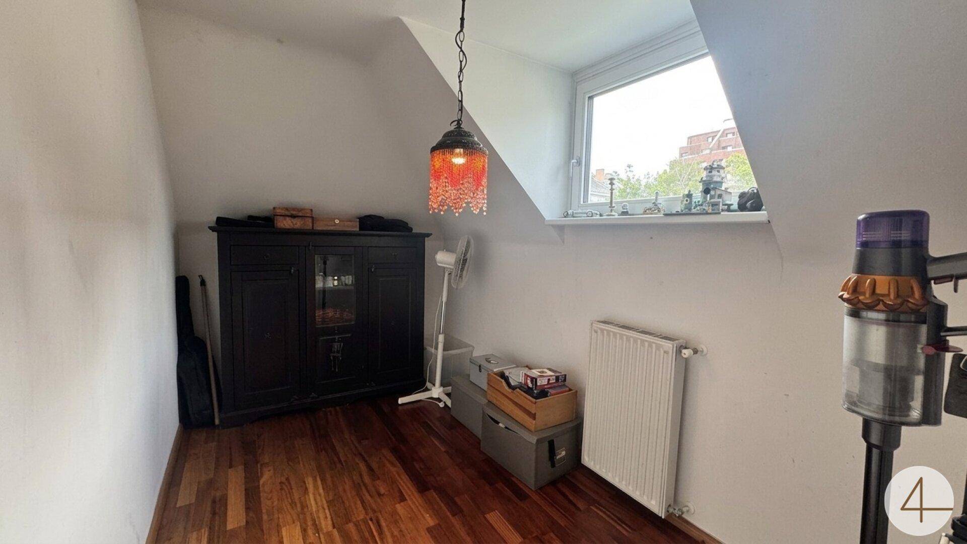 Dachgeschossraum mit Schrank, Heizkörper und Fenster.