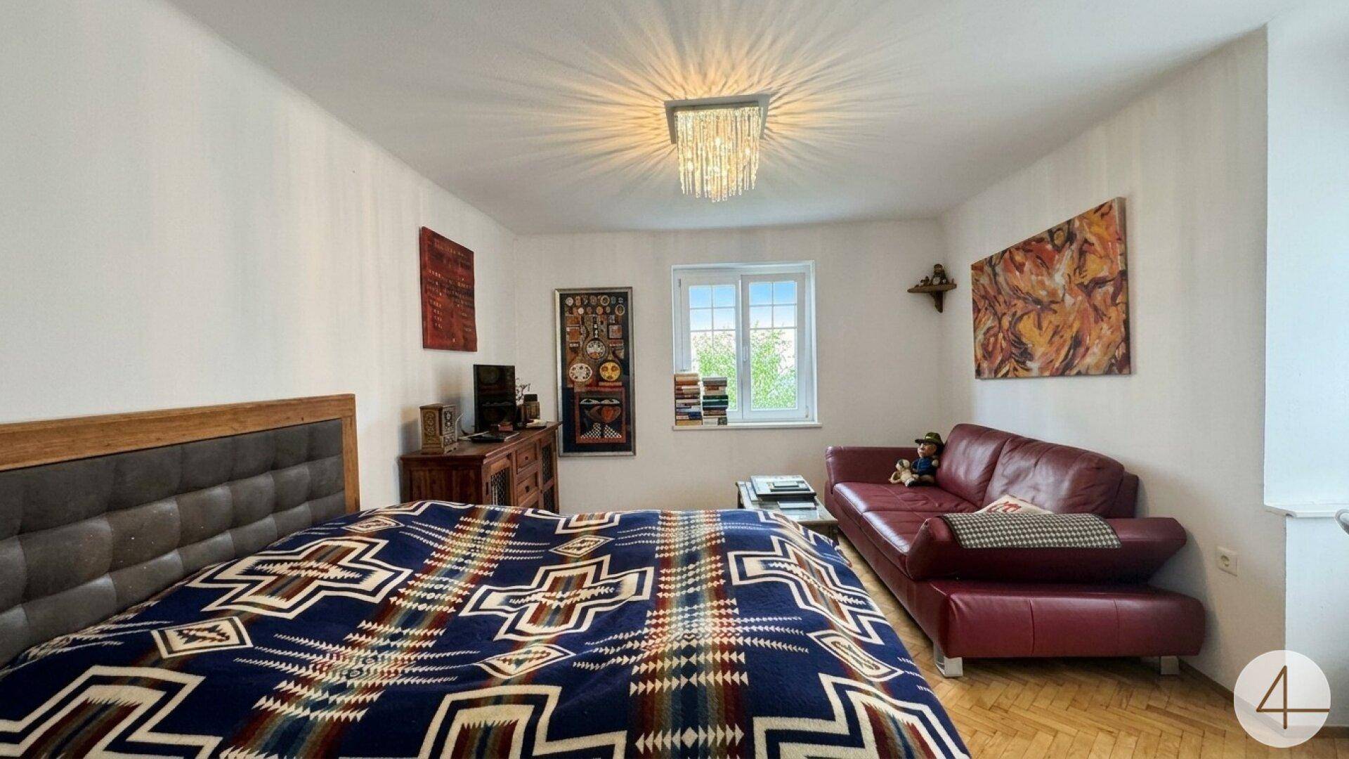 Gemütliches Schlafzimmer mit Doppelbett, Ledersofa und Parkettboden.