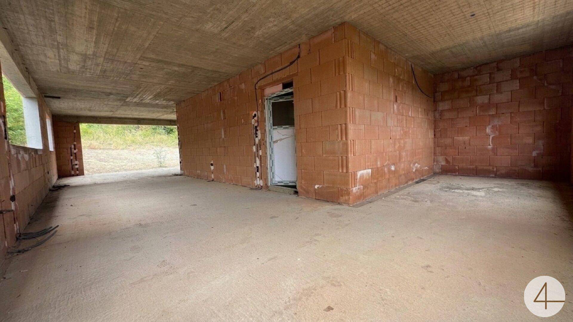 Großer, unfertiger Innenraum mit Ziegelwänden und Betonoberflächen, bereit für den Ausbau.