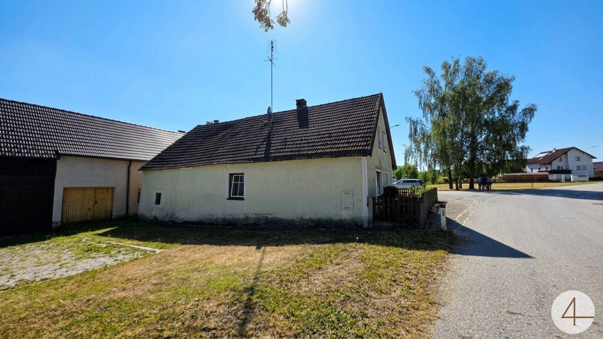 Rückansicht eines Teils des Hauses mit einfacher Fassade, kleinem Fenster und trockenem Rasen.