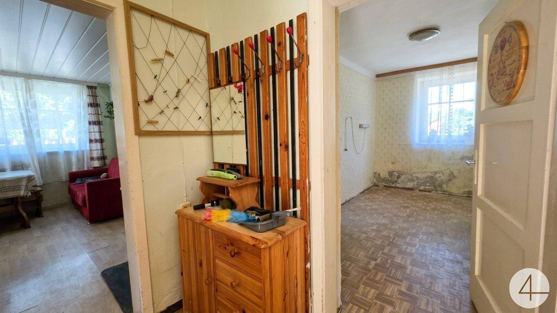 Flur mit Holzkommode, Garderobe und Blick in angrenzende Zimmer.