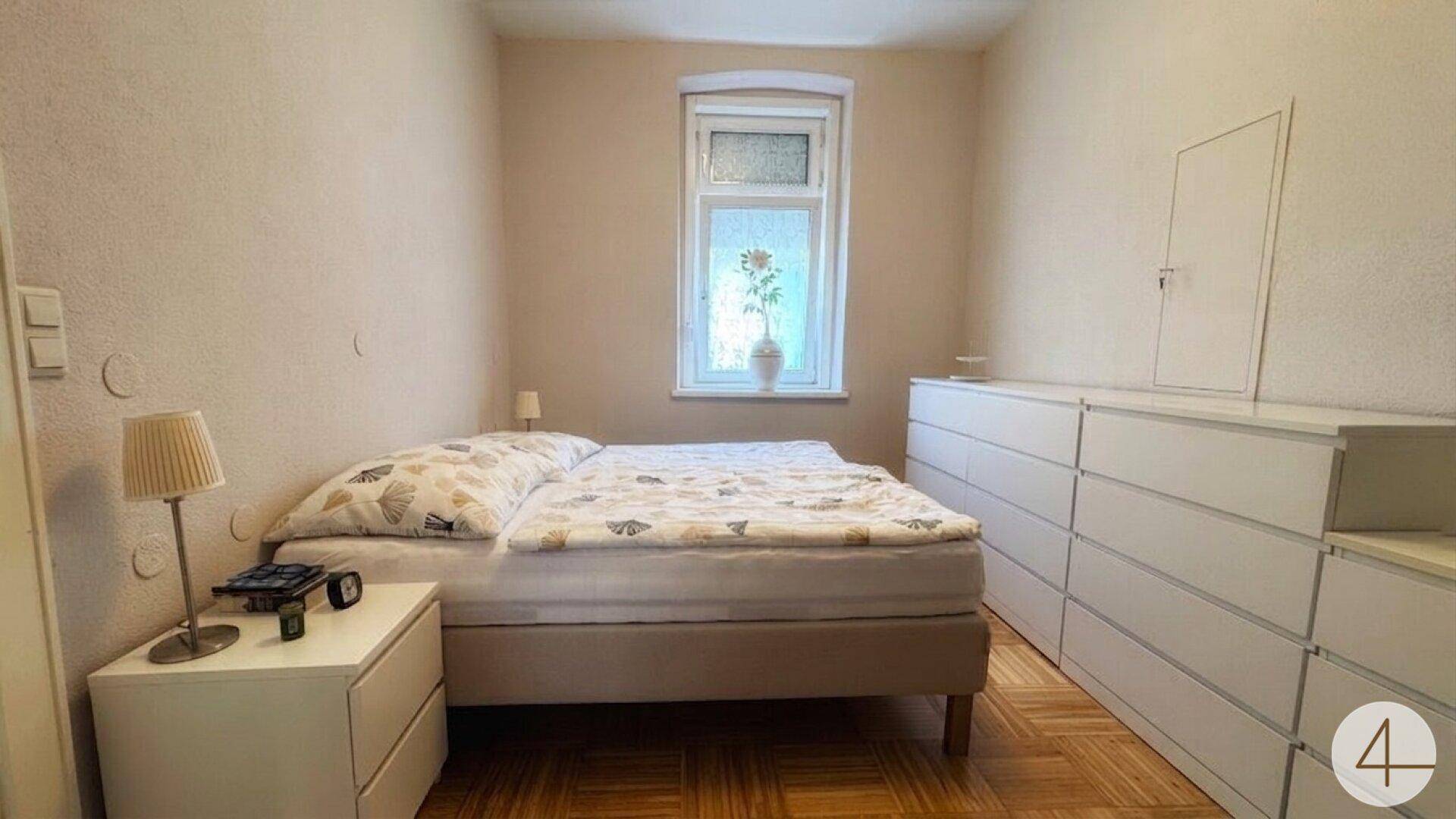 Gemütliches Schlafzimmer mit Doppelbett, weißen Kommoden und einem Fenster für natürliches Licht.