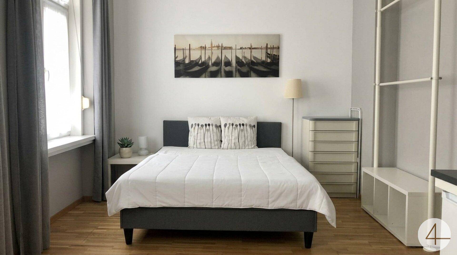 Schlafzimmer mit Doppelbett, Kommode und offenem Kleiderschranksystem.