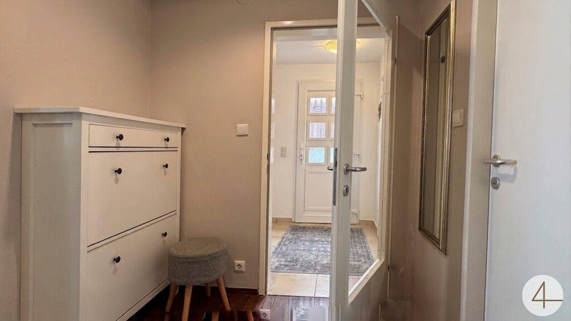 Funktionaler Flur mit Schuhschrank, Spiegel und Blick auf eine weitere Tür.