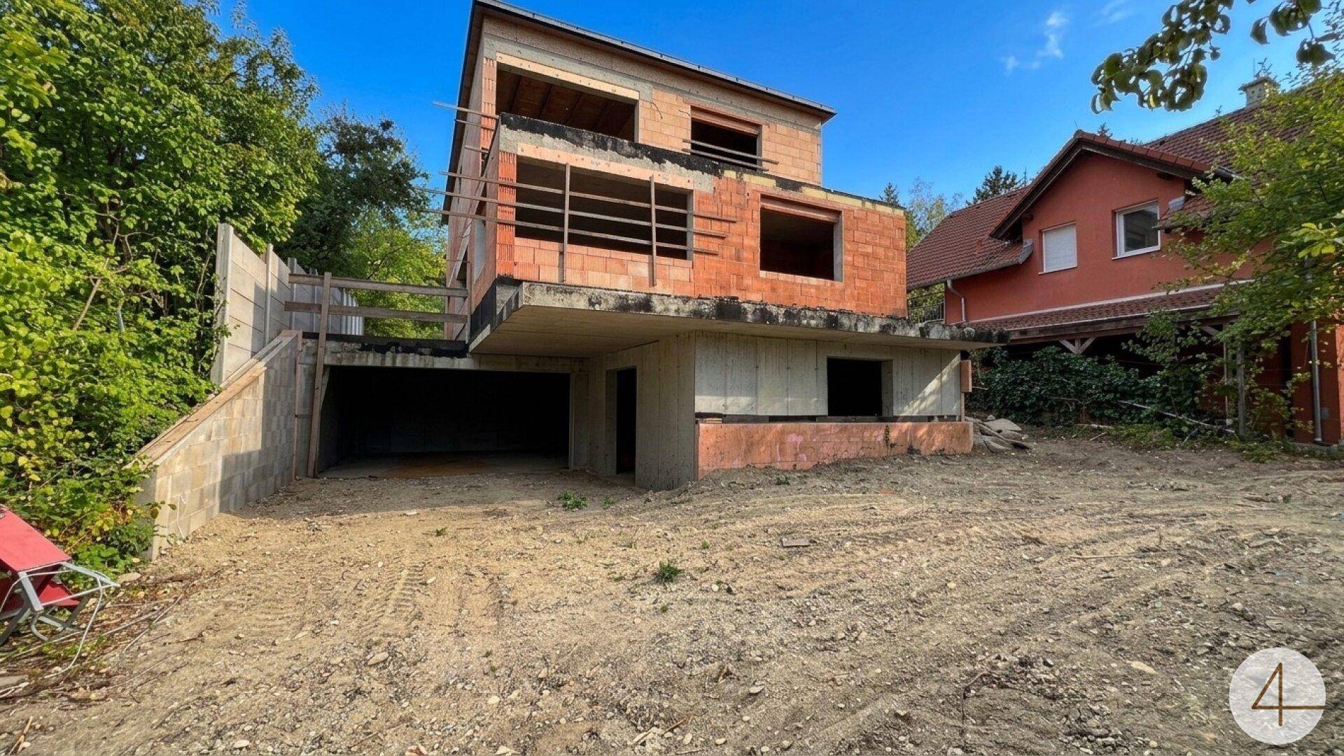 Rohbau eines modernen Hauses mit Garage im Untergeschoss und unverputzten Ziegelwänden.