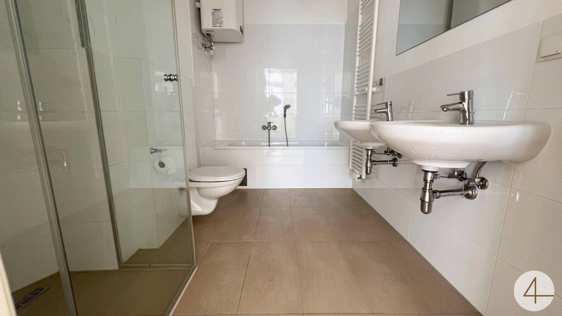 Modernes Badezimmer mit zwei Waschbecken, Badewanne, begehbarer Dusche und weißen Fliesen.