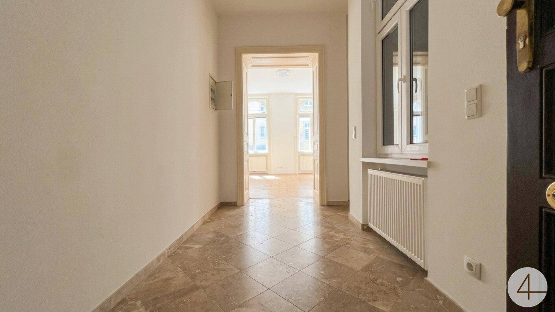 Heller Flur mit Fliesenboden und Blick in angrenzende Zimmer mit Parkett, einladender Eingangsbereich.
