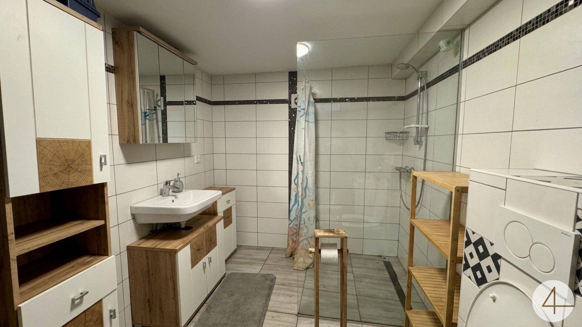 Modernes Badezimmer mit Duschkabine, Waschbecken und Holzmöbeln.