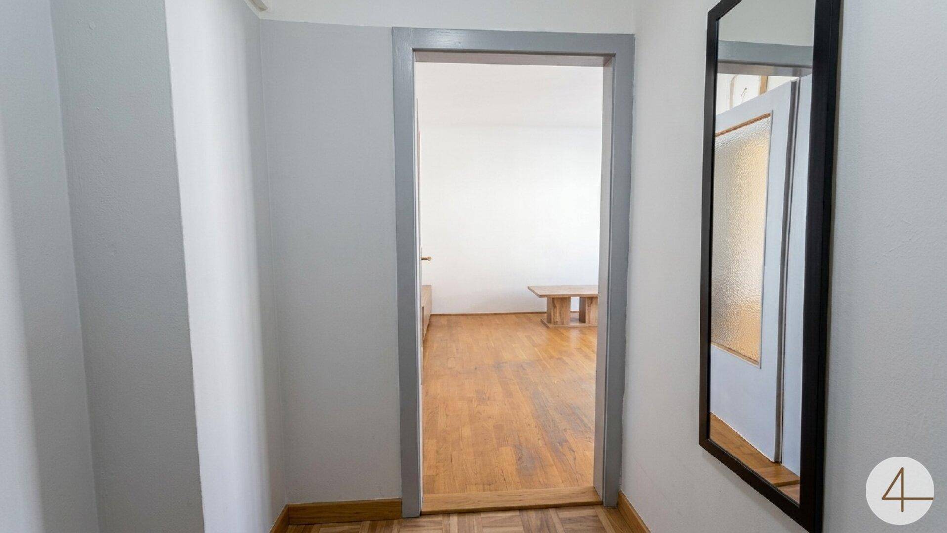 Eingangsbereich mit Spiegel und Blick in einen angrenzenden Wohnraum.