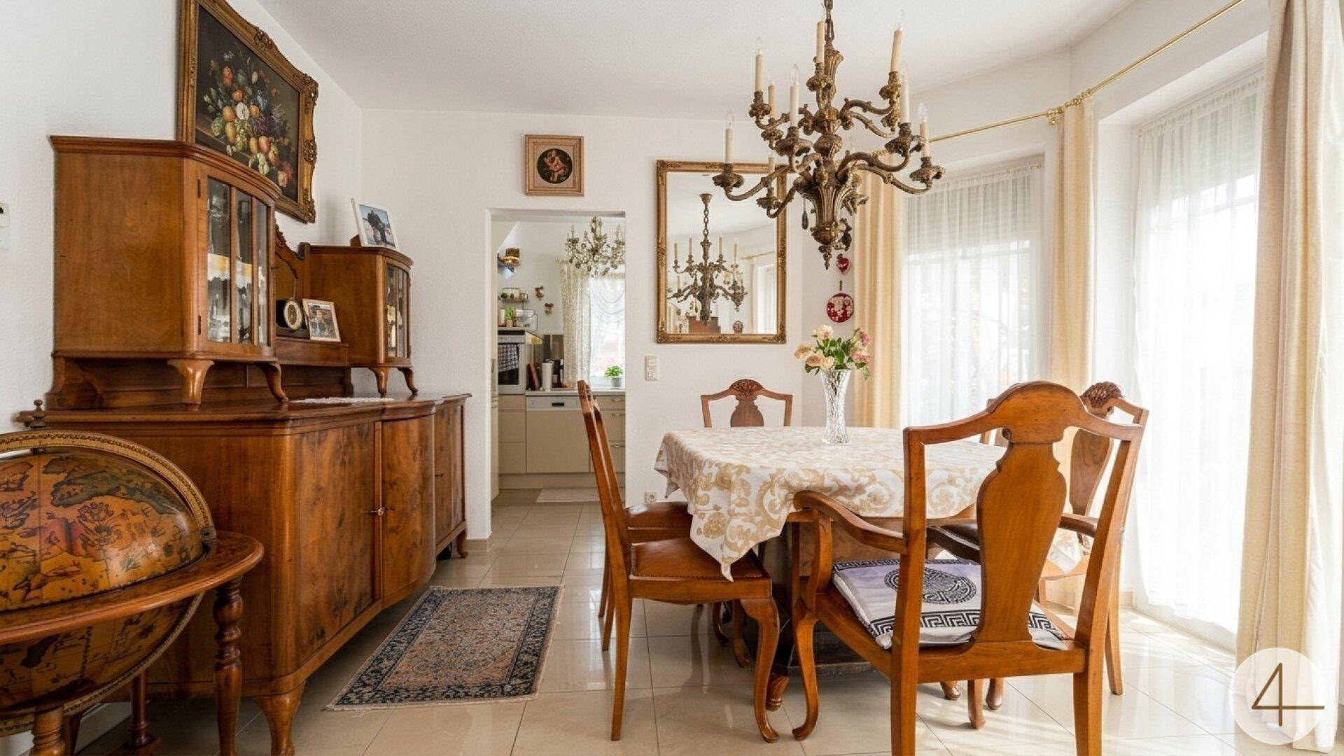 Klassisches Esszimmer mit Holztisch, Stühlen und einem großen antiken Holzschrank.