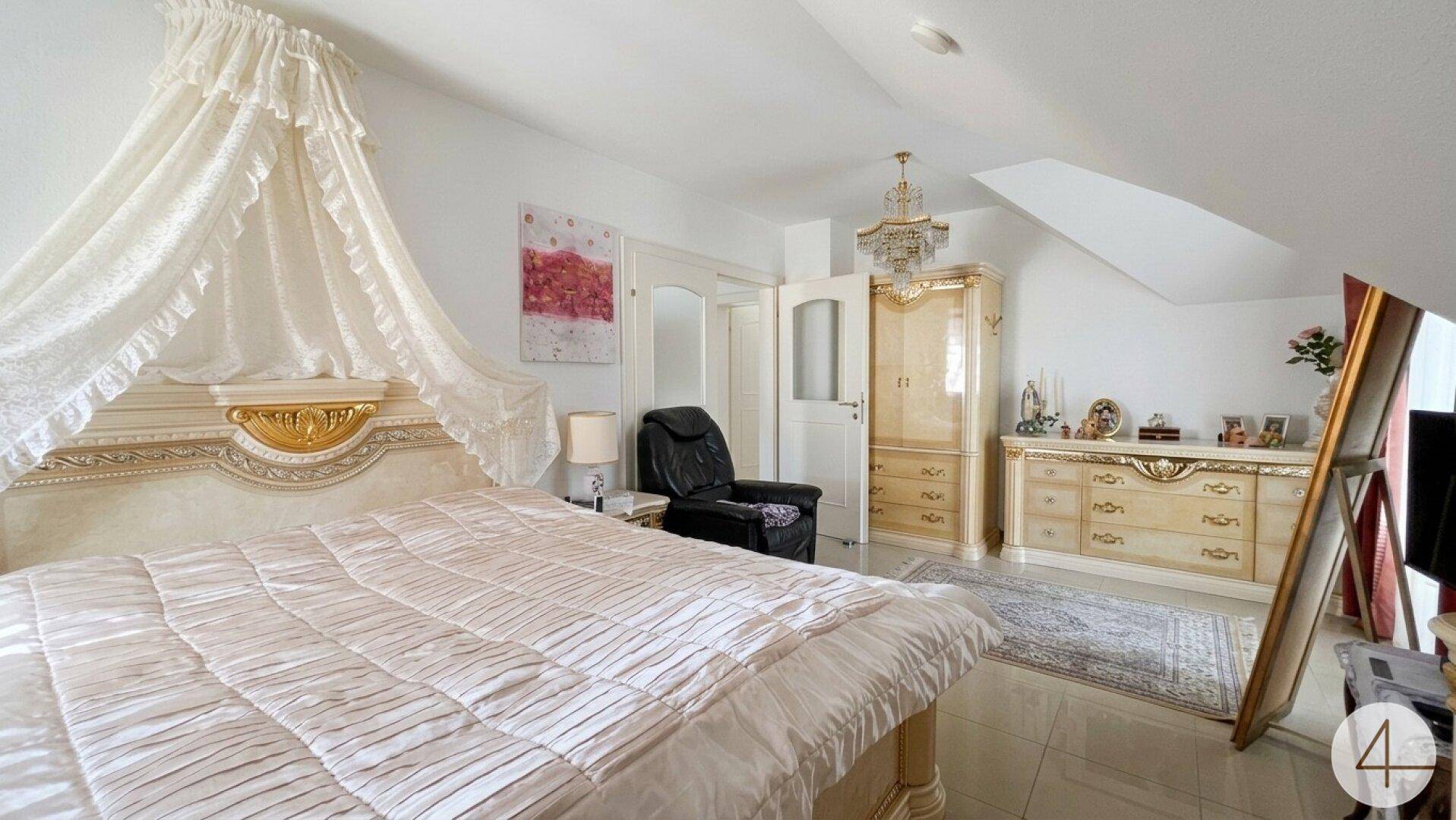 Geräumiges Schlafzimmer mit großem Bett, traditionellen Möbeln und Dachschrägen.