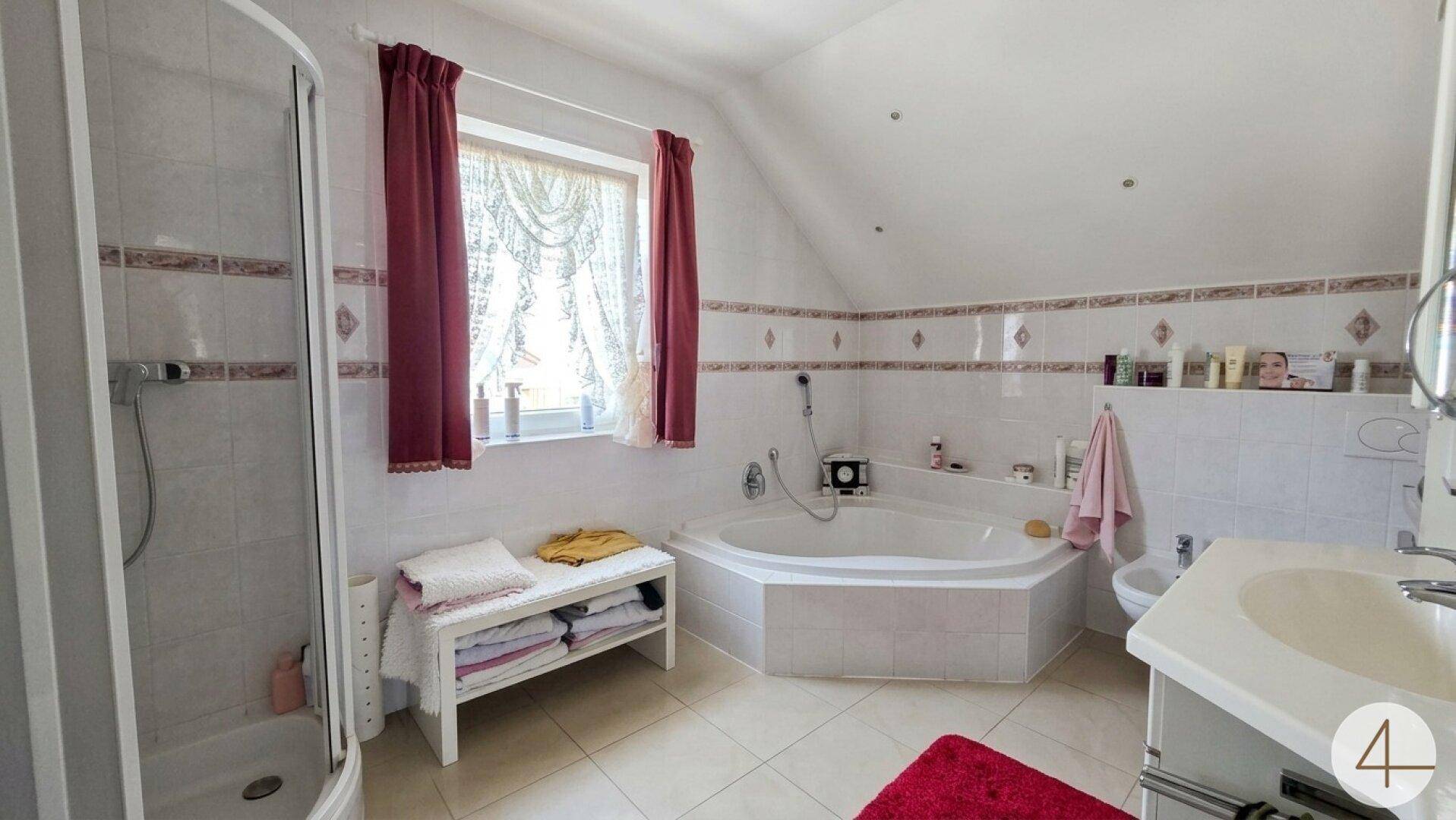 Badezimmer mit Eckbadewanne, Duschkabine, Bidet und Fenster für Tageslicht.