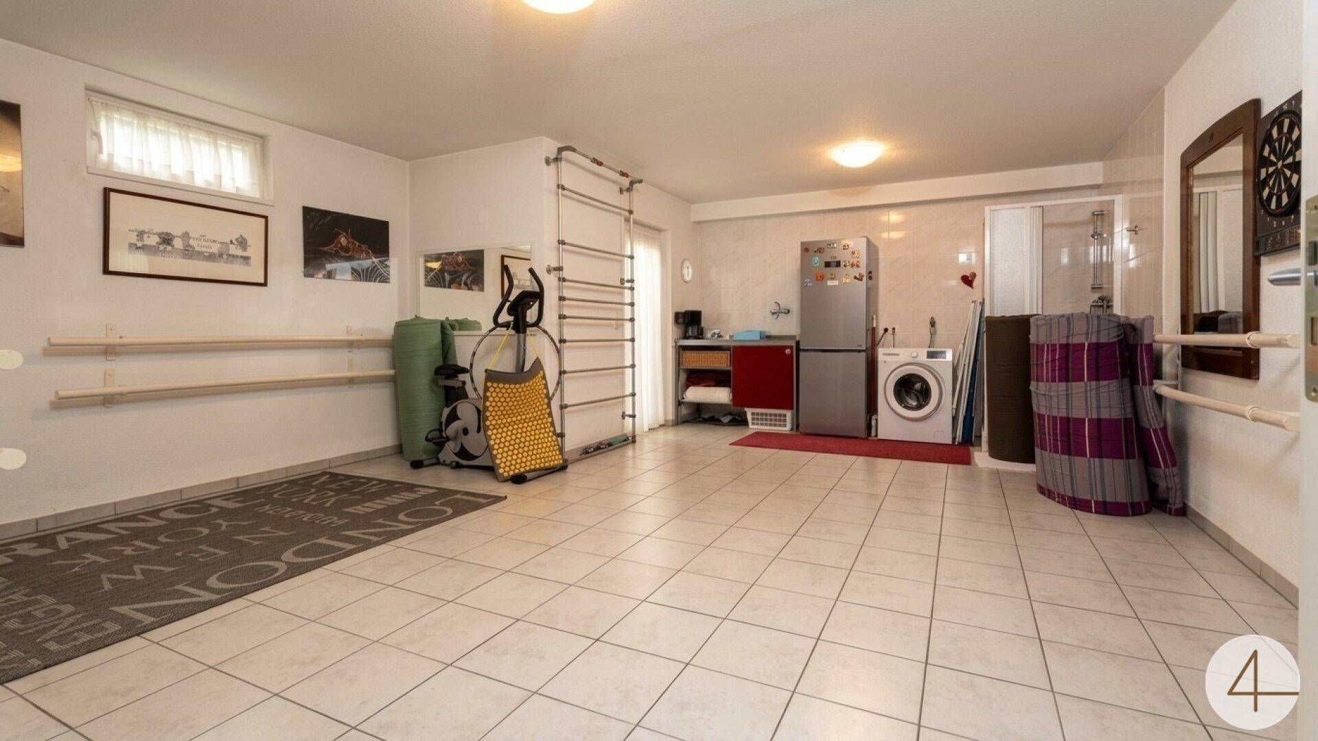 Geräumiger Kellerraum mit Fliesenboden, Fitnessgeräten und Waschküchenbereich.