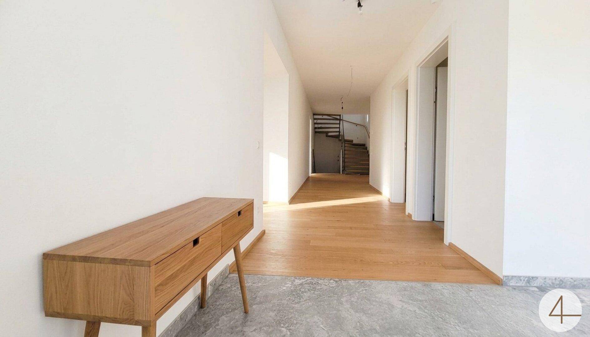 Heller Flur mit Holzboden, der zu einer Treppe führt, und einer modernen Holzkonsole.