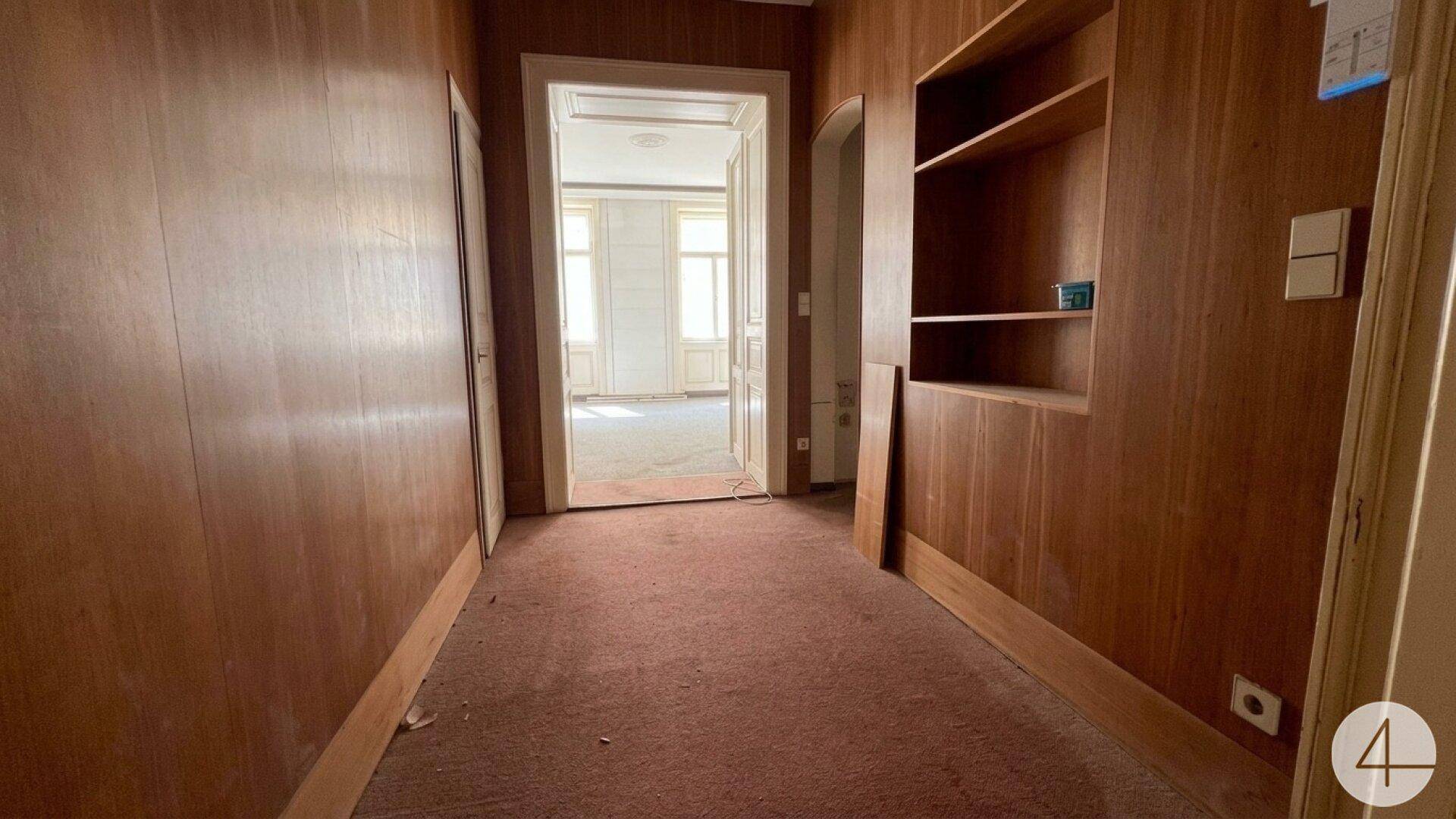Langer Flur mit Holzvertäfelung und Teppichboden, führt zu weiteren Räumen.