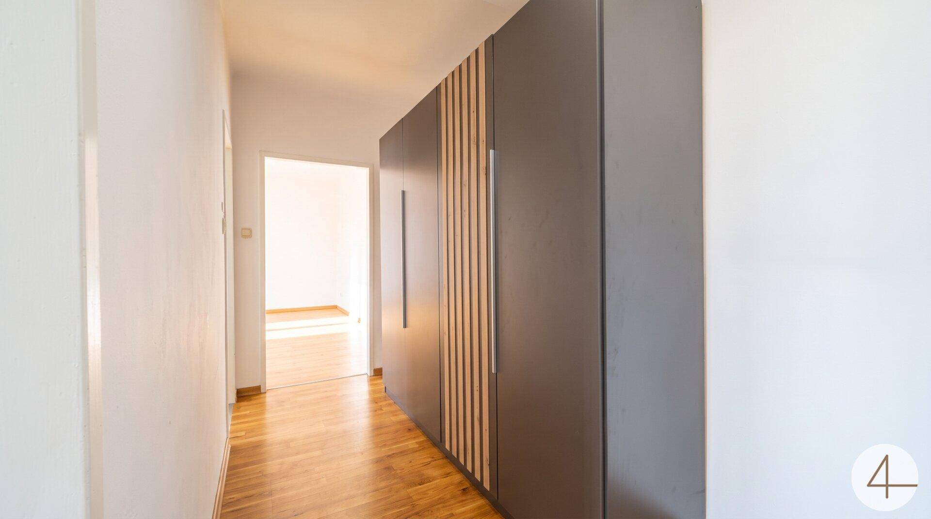 Heller Flur mit Holzboden und einem modernen, integrierten Kleiderschrank.