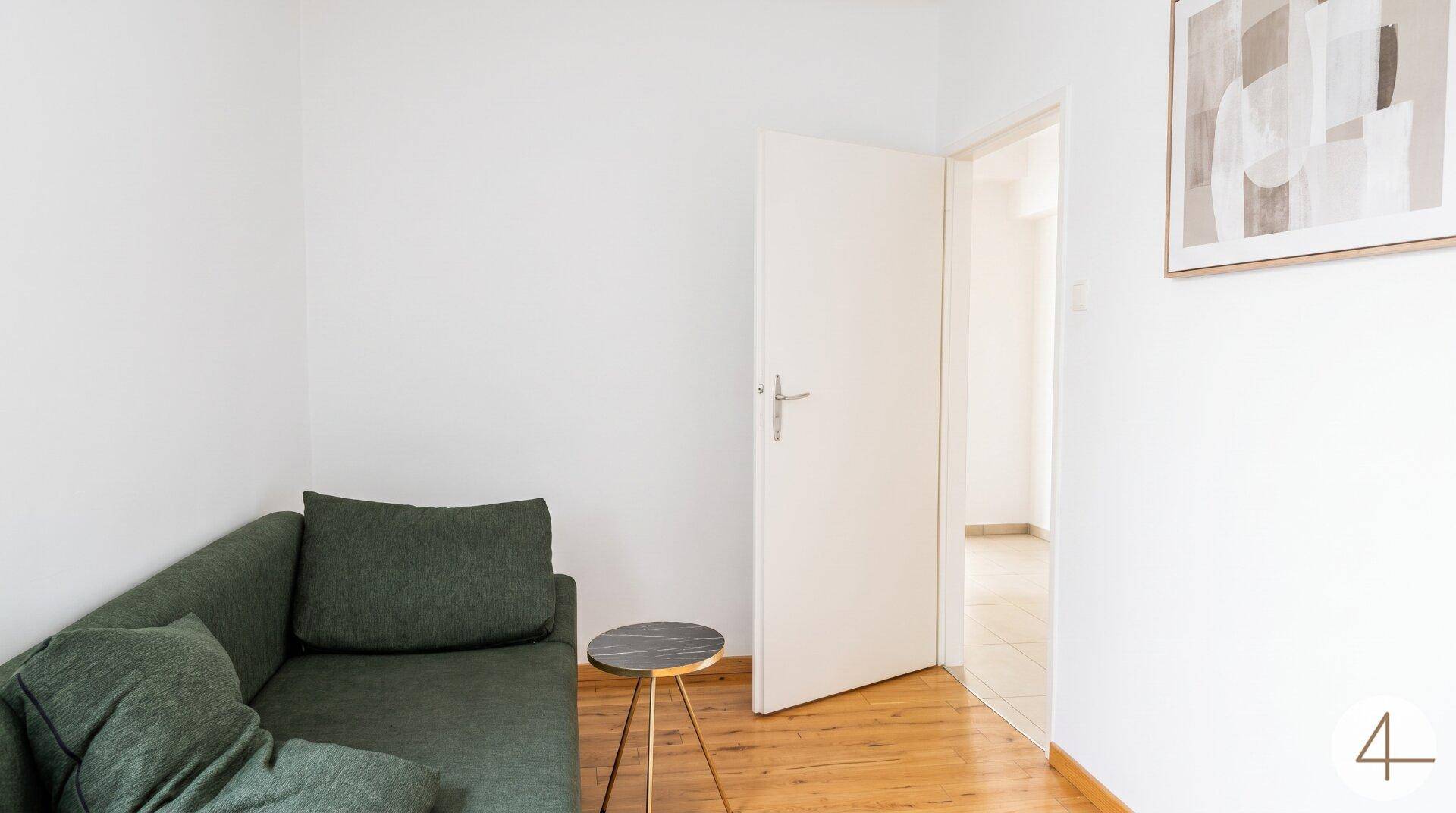 Gemütlicher Bereich mit grünem Sofa und Holzboden, ideal als Leseecke oder kleines Wohnzimmer.