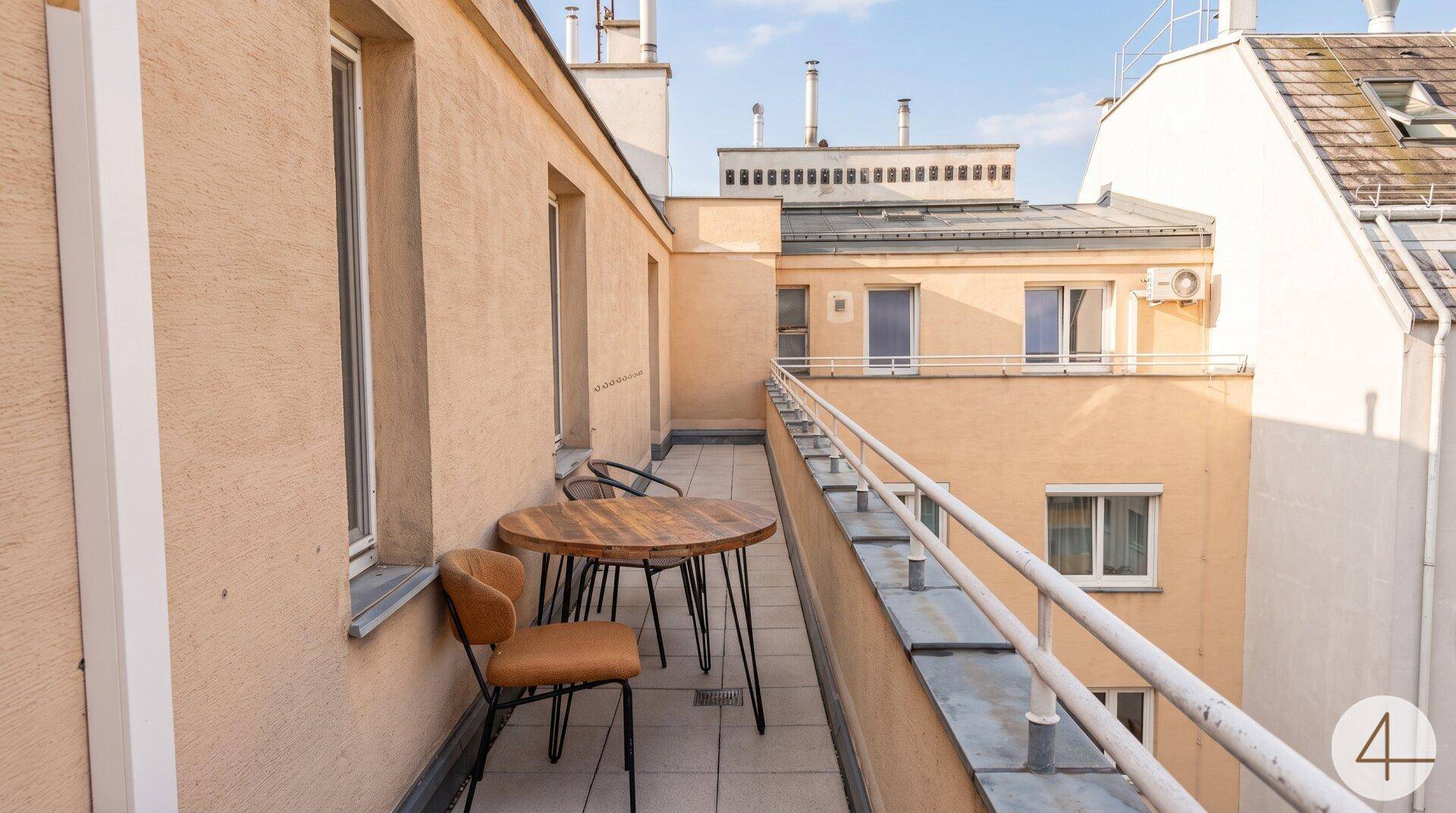 Langer Balkon mit Sitzgelegenheiten und Blick auf die umliegenden Gebäude.