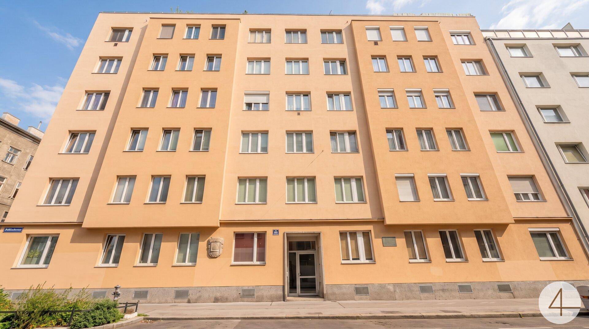 Mehrstöckiges Wohngebäude mit vielen Fenstern und einer hellen Fassade.