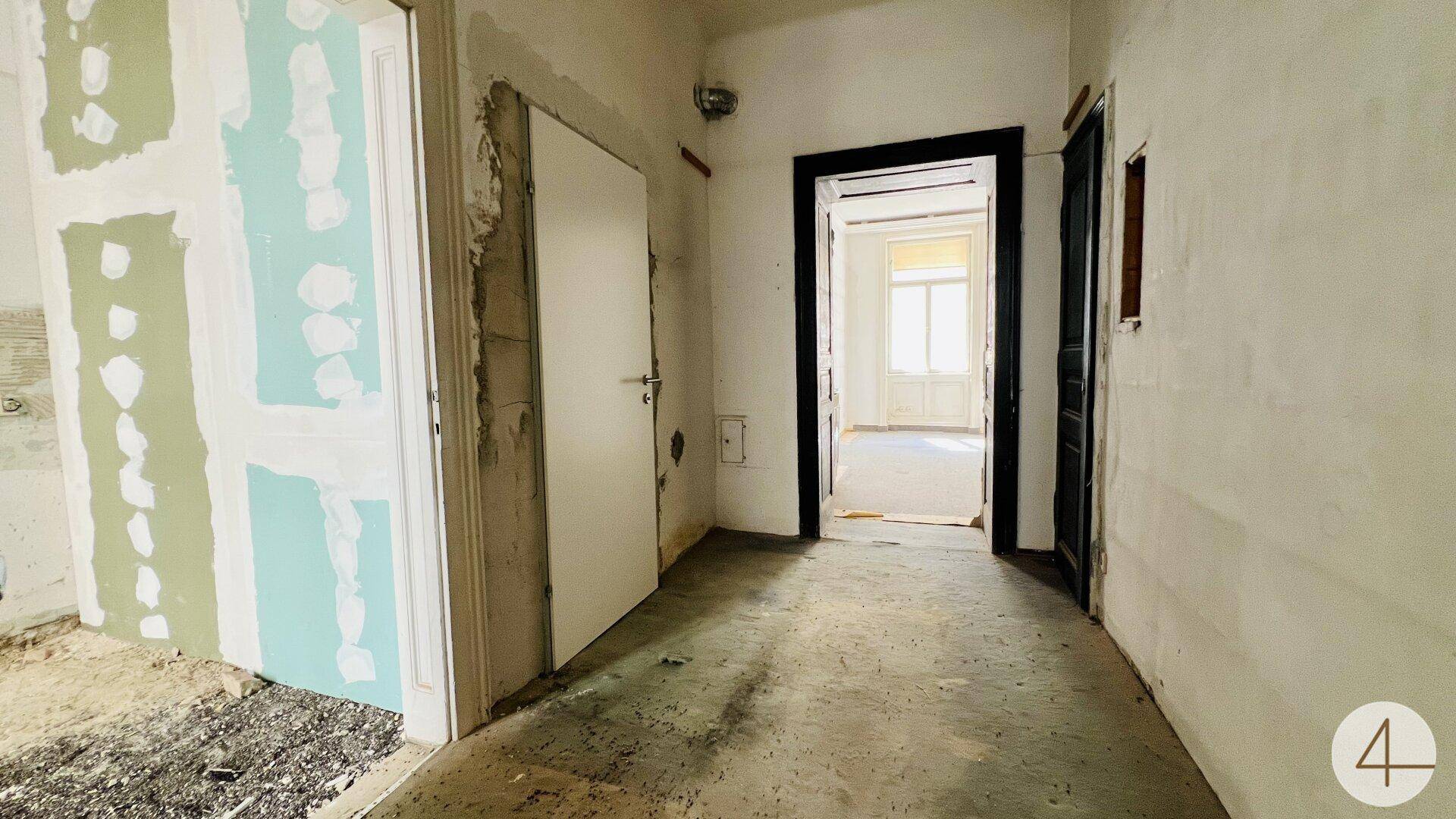 Flur im Renovierungszustand mit mehreren Türen und Rohbauwänden, wartet auf Fertigstellung.