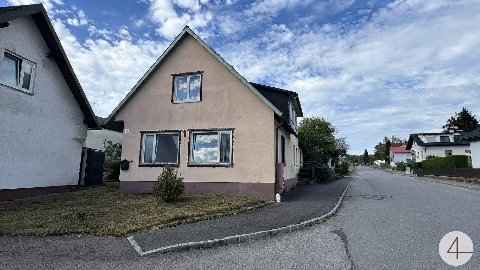 Ansicht des Wohnhauses von der Straßenseite mit Vorgarten und einfacher Architektur.