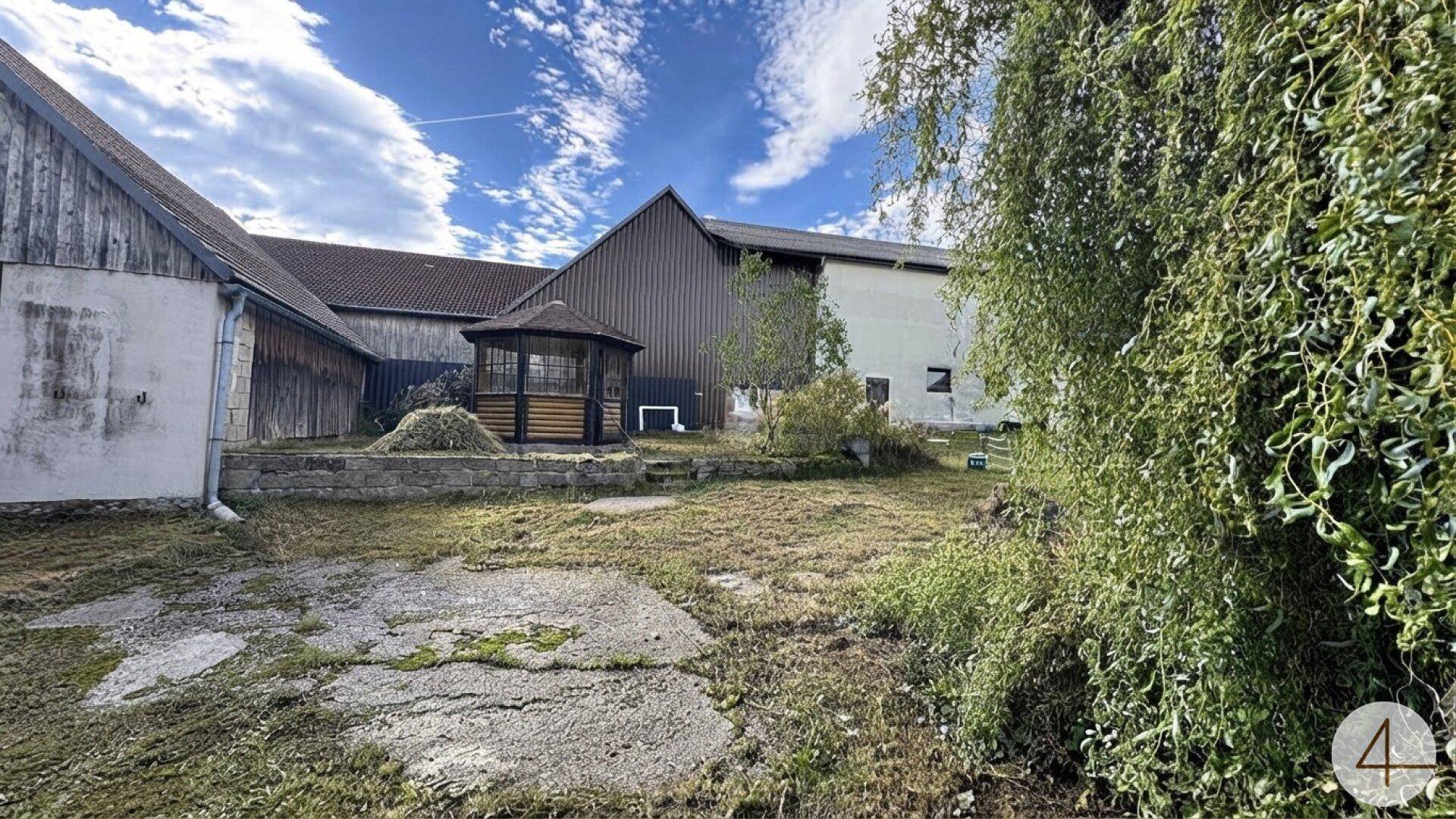 Großer, naturbelassener Gartenbereich mit einem Gartenpavillon und angrenzenden Wirtschaftsgebäuden.