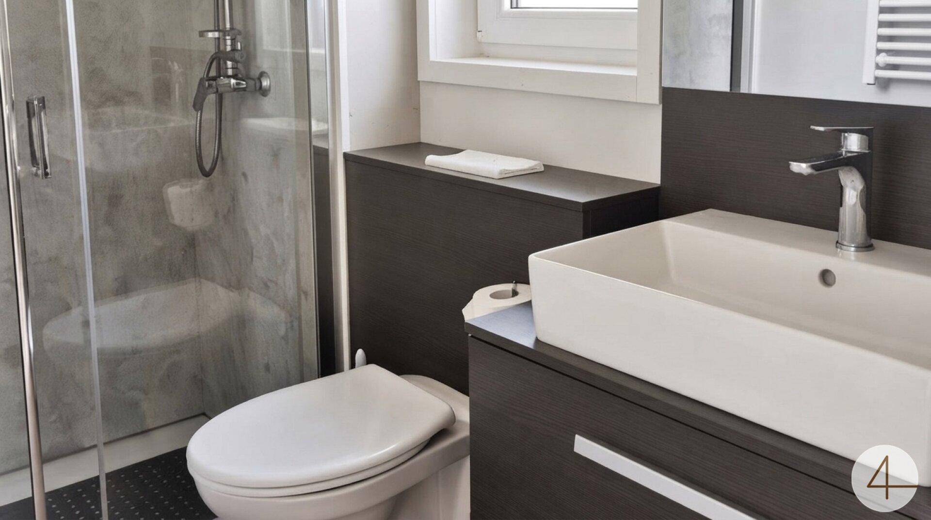 Modernes Badezimmer mit Duschkabine, Waschbecken und dunklen Holzmöbeln.