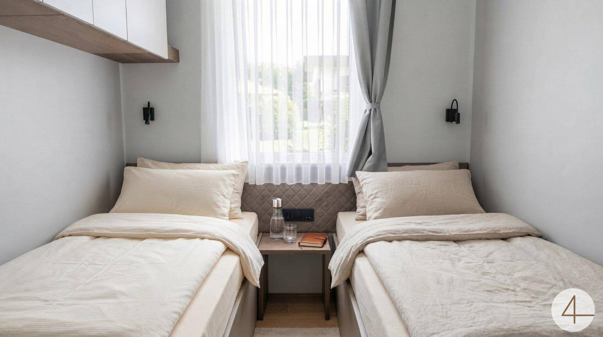 Helles Schlafzimmer mit zwei Einzelbetten, Nachttisch und Fenster mit Vorhängen.