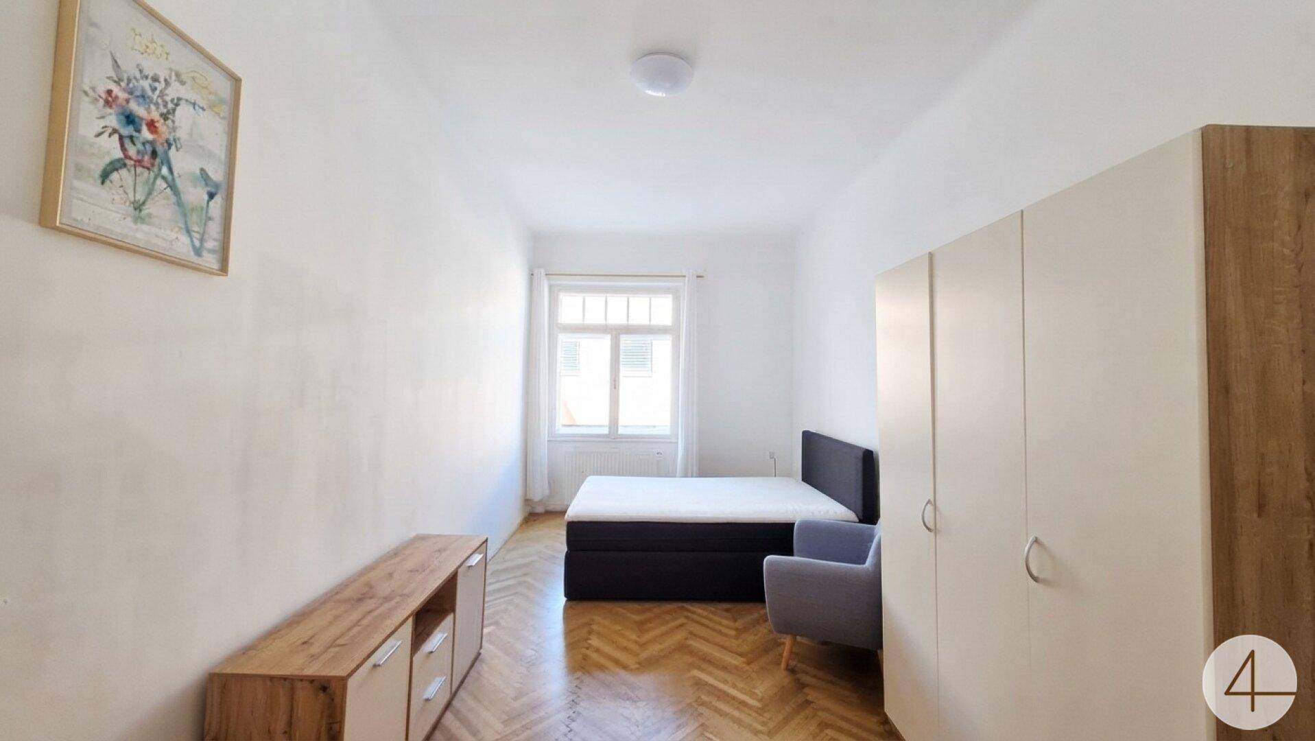 Gemütliches Schlafzimmer mit Doppelbett, großem Kleiderschrank und hellem Fischgrätparkettboden.