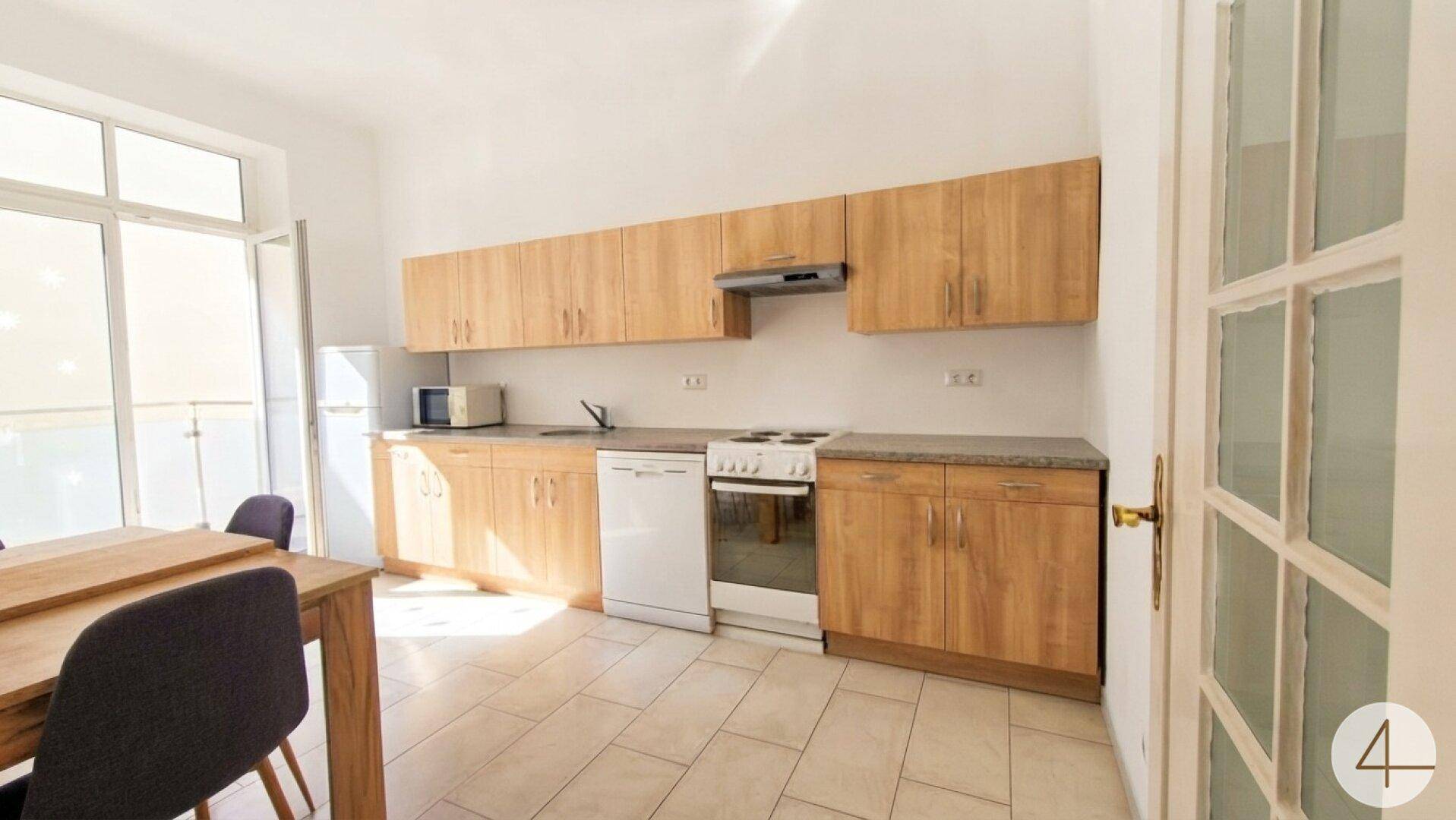 Helle Küche mit Holzschränken, modernen Geräten und Zugang zu einem Außenbereich durch eine große Tür.