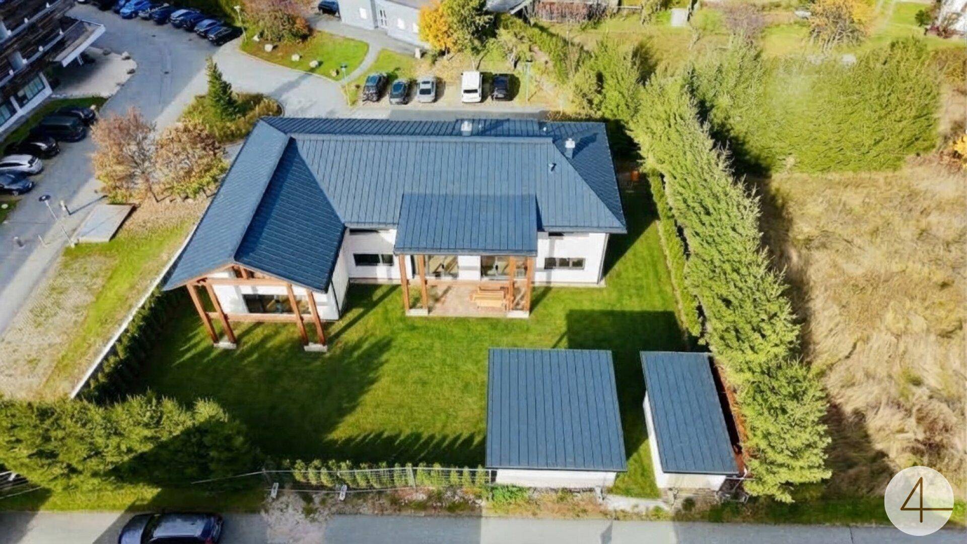 Vogelperspektive des modernen Hauses mit großem Garten, umgeben von Hecken und weiteren Gebäuden.