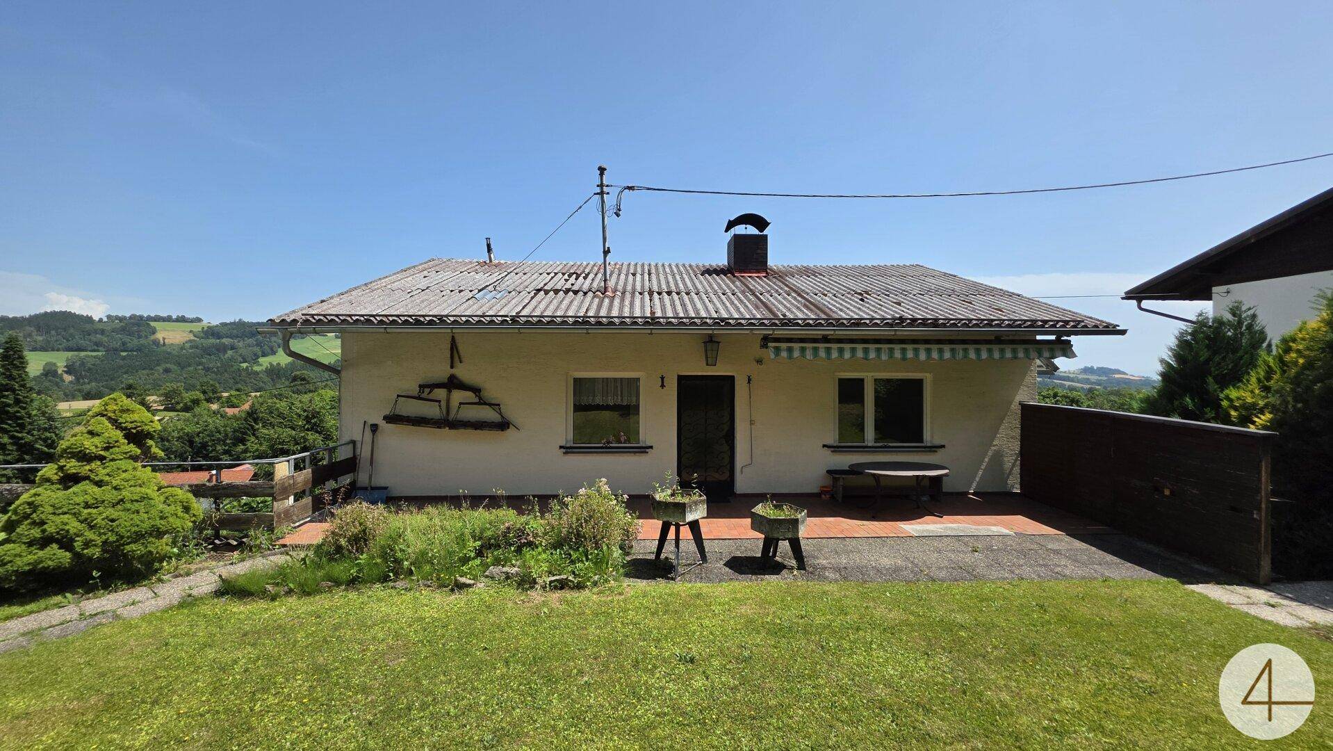 Einfamilienhaus mit Satteldach, Garten und weitem Blick über die grüne Landschaft an einem sonnigen Tag.