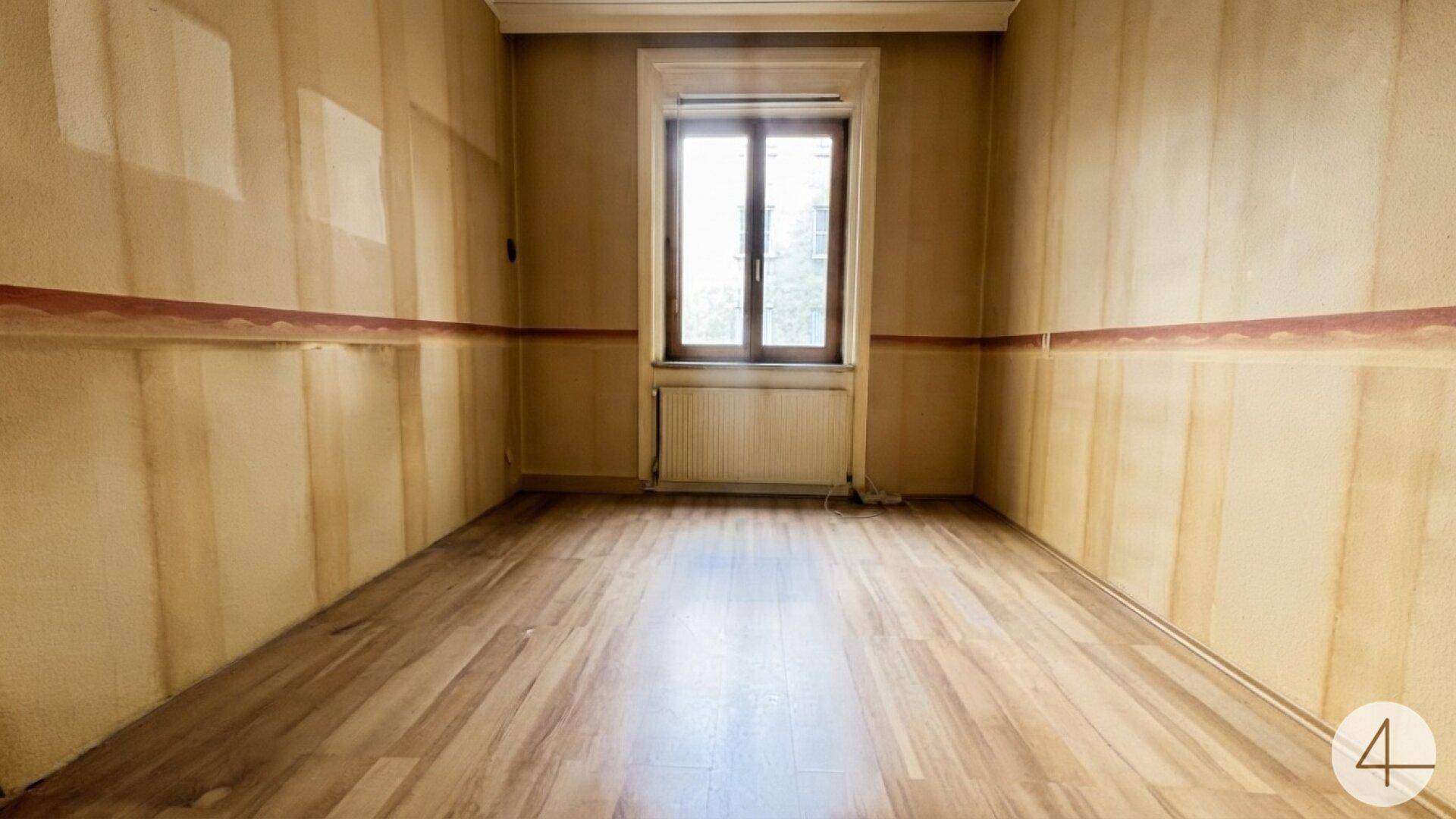 Leeres Zimmer mit Holzboden und renovierungsbedürftigen Wänden, bereit für eine Neugestaltung.